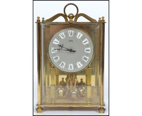 A 20th century glass cased mantle clock with columned front faceted hands and a roman numeral chapter ring, the clock raised 