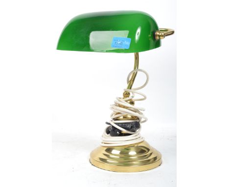 A vintage 20th century bankers desk lamp having an adjustable green glass shade raised on a brass support and circular base.