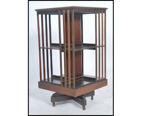 An Edwardian mahogany revolving bookcase having slatted sectional body raised on swivel column with quadruped ceramic castors