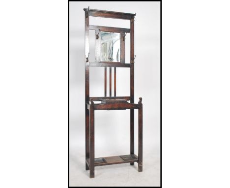 A 1920's oak hallstand having a central glove box with upright back having hooks and mirror glass to centre over a stick stan