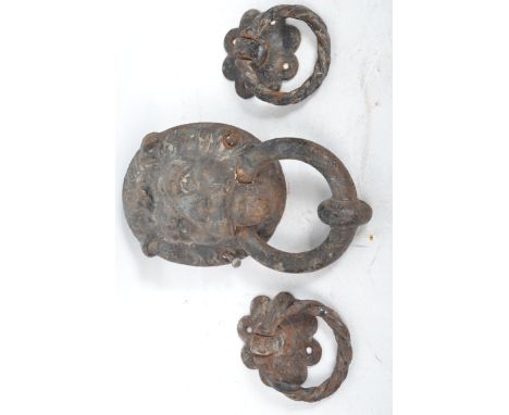 An early 20th century cast iron lion mask door knocker along with a pair of smaller floral door knockers.