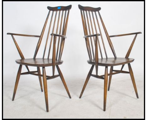 A pair of mid 20th Century pair of Ercol  Goldsmith Windsor beech wood and elm carver dining chair. Measures 97cms x 62cms x 