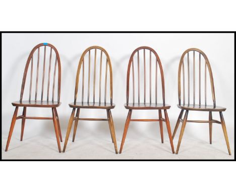 A set of 4 20th century Ercol windsor pattern beech and elm dining chairs with saddle seats and turned legs united by stretch