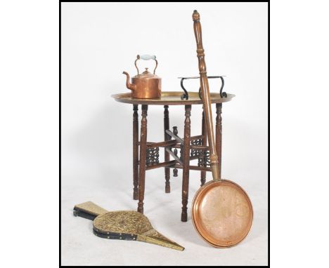 An early 20th century metamorphic Anglo - Indian folding brass occasional table together with a pair of bellows, copper teapo