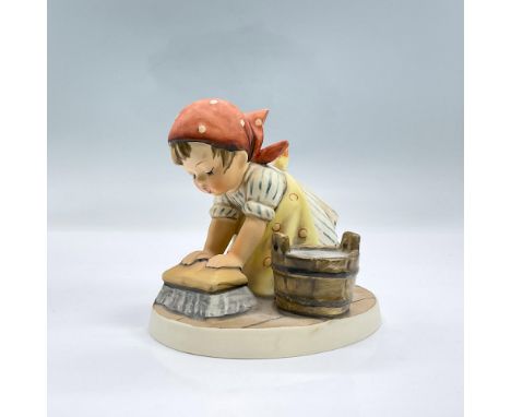 Hand painted figure of a girl in a headscarf and apron kneeing down scrubbing the floor with a cleaning brush. A bucket of so