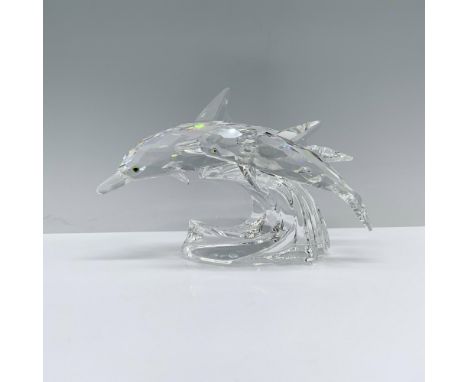 A clear crystal sculpture depicting a mother and child dolphin swimming gracefully side by side over a wave, their eyes adorn