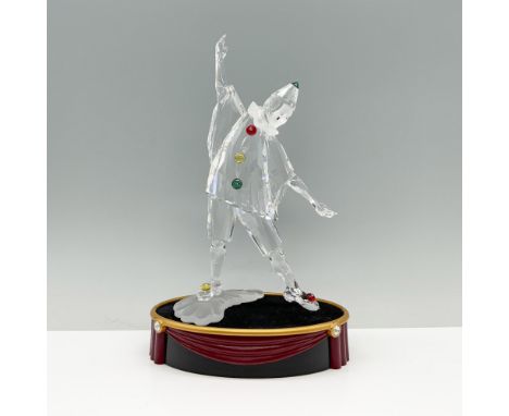 A jester figure striking an open-armed pose, complemented by green, red, and yellow crystals joined by an oval base with a dr