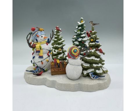 Adult snowman is tangled up in the lights and watches as the child snowman decorates the forest trees. Cardinals and blue jay