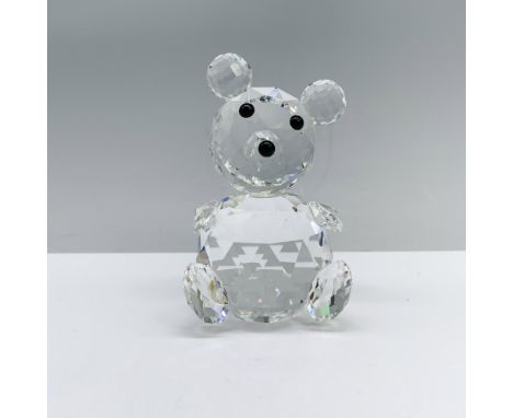 A large bear adorned with black crystal eyes and snout, seated on its bottom with arms and legs relaxed, head gently tilted. 