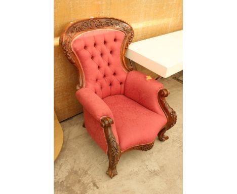 A VICTORIAN STYLE BUTTON SPOON BACK CHAIR WITH FOLIATE CARVING TO TOP RAIL AND FRONT KNEES 