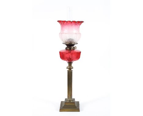 A Victorian oil lamp, the brass column with a cranberry glass reservoir and clear to cranberry and frosted shade, 78cm high