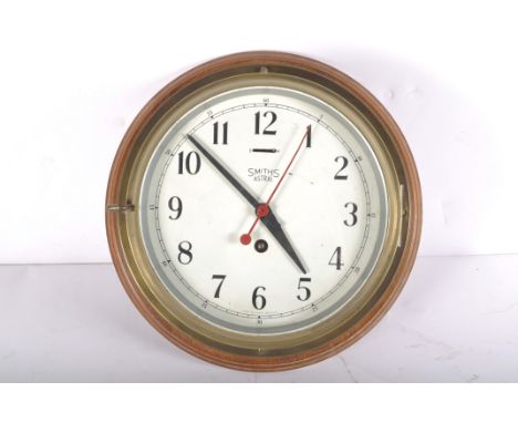 A Smiths Astral brass bulk head clock, the 7 1/2" dial on a brass body and wooden wall mount, with key, mount 29cm diameter