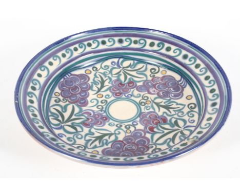 An early 20th Century, circa 1920's, Carter Stabler Adam Poole pottery charger in the purple grapes design having bands of pu