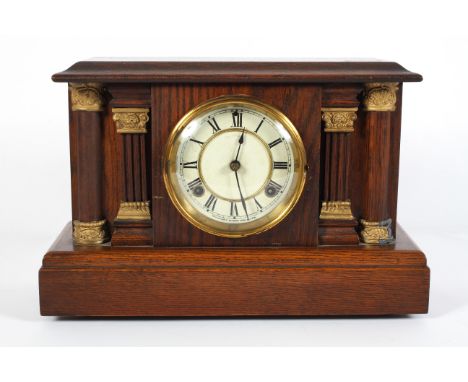 An oak striking mantel clock, early 20th century, of architectural form, the painted metal dial with Roman numerals, flanked 