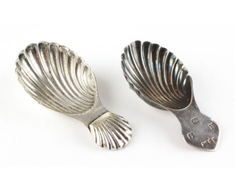 A silver shell-shaped caddy spoon and a white similar white metal example, the first dated 1983