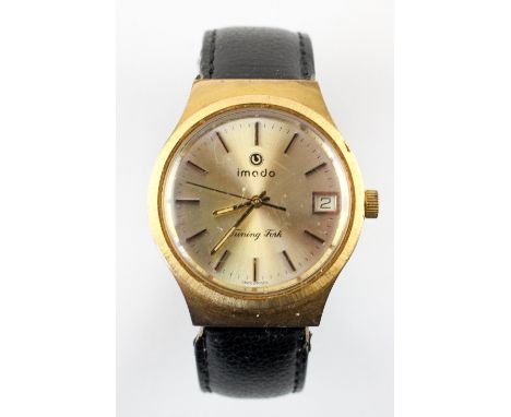 A gold plated wristwatch. Circular champagne dial, signed Imado, Turning fork. Baton markings with date feature. Black leathe