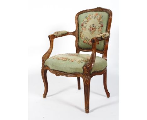 A French carved Louis XV style tapestry fauteuil, the top rail carved with flowers, within reeded rocaille frame, upholstered