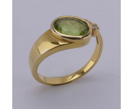An oval facetted peridot Ring, collet set in 14ct yellow gold with diamond point accent, Size M, 3.3g. 
