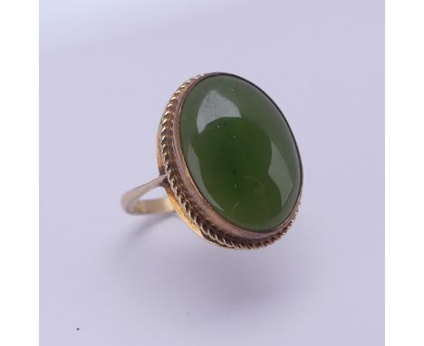 A 9ct gold mounted jade Ring, the oval cabochon stone approx. 18mm long, in twist mount, Size O½, 4.2g. 