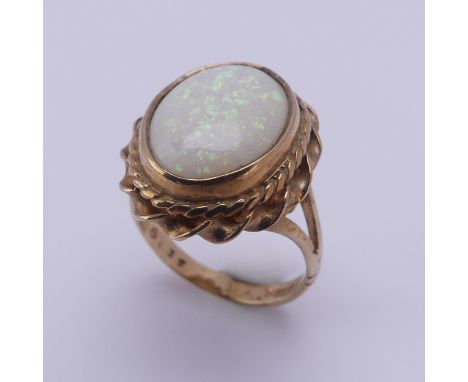 A 9ct gold mounted opal Ring, the oval cabochon stone approx. 13.4mm long, in twisted mount, Size L, 4.8g. 
