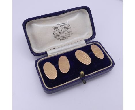 A cased pair of 9ct gold oval Cufflinks, each side with engine turned decoration, chain between, approx. total weight 7.4g. 