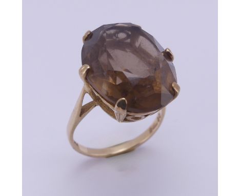 A smoky quartz Dress Ring, the oval facetted stone 19.7mm long, six claw set in 9ct yellow gold, Size N, 5.8g. 