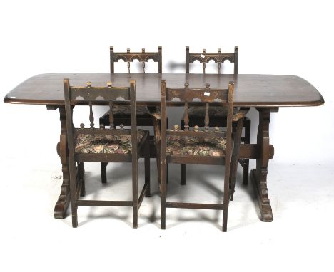 A mid-century Ercol table and a set of four carved chairs. The dark Ercol table having shaped supports united by a single str