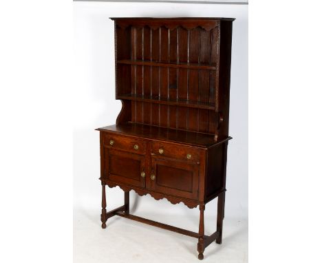 An early 20th century oak dresser sideboard. Having two plate shelves above, two short drawers over a two door cupboard above