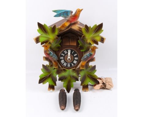 A German 20th century cuckoo clock. With carved and painted decoration, a pair of pine cone weights present, no pendulum. H34