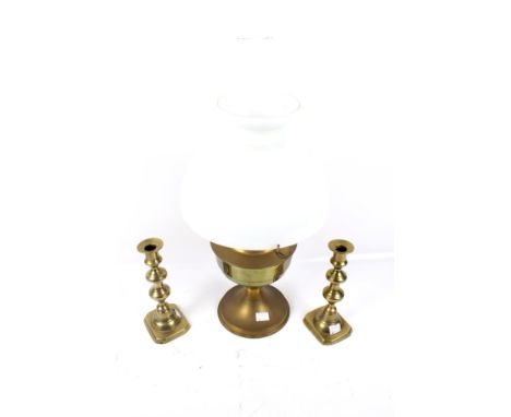 A brass oil lamp and two brass candlesticks. The lamp with a white glass shade. Max H53cm