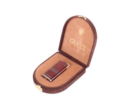 A Gucci lighter. The gilt metal body with bronze, green and red striped decoration, marked 'Gucci Italy', L6cm, within a brow