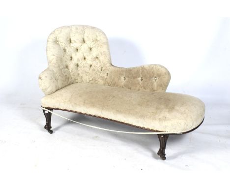 A Victorian chaise longue. The mahogany frame with carved details, upholstered in cream damask fabric with a button back, on 