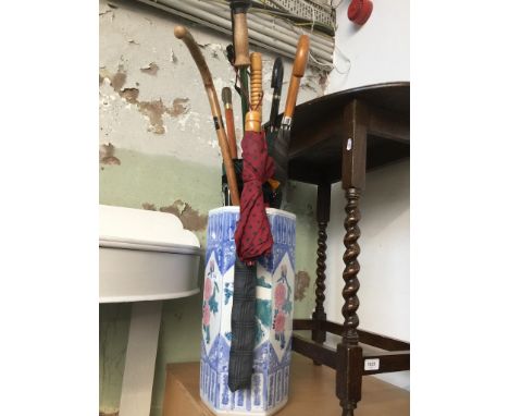 An eastern style ceramic stick stand and quantity of sticks and umbrellas 