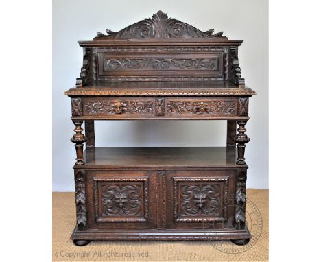 A Victorian carved oak buffet, with raised back above two drawers with lion mask handles, above two cupboard doors, on bun fe