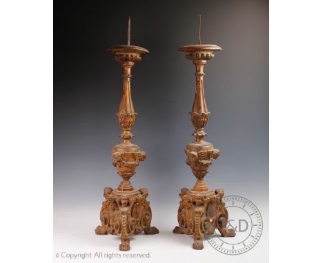 A pair of 19th century and later carved softwood pricket altar sticks, carved with cherubs and further winged figures below a