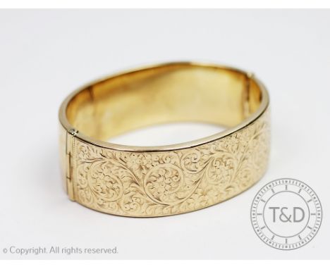 A Victorian style 9ct gold hinged bangle, Smith and Pepper, Birmingham 1947, of half engraved form and decorated with scrolli
