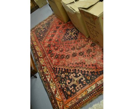 Persian style carpet with central hooked medallion and multiple borders on a red and midnight blue ground, approximately 7.5f