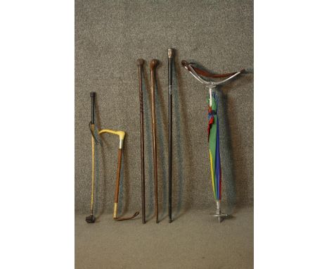 A collection of three walking canes, one Chinese with a silver top along with an umbrella/shooting stick and two riding crops