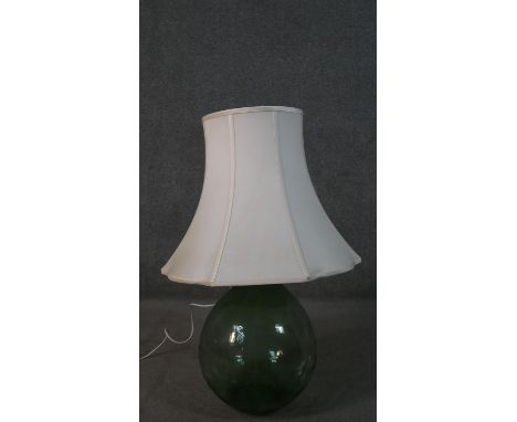 A large green blown glass demijohn converted into a lamp. H.90cm 