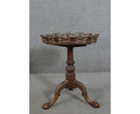 A Victorian walnut tripod table, the hexagonal tilt top with an ornately carved and pierced edge, on a turned, carved and flu