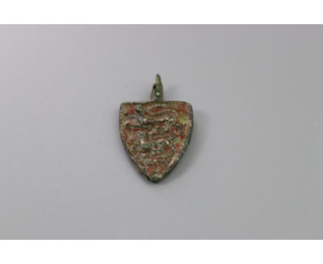 The bronze horse harness pendant with red enamel, displaying three lions passant gardant. Found in Wiltshire. L:3cm Good over