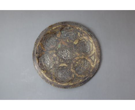 A large Cairo Ware silver inlaid brass plate, 19th century. With silver inlaid inscription on the front. W:34cm Age related p