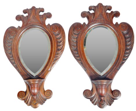 A pair of 19th Century Victorian carved oak hanging hall mirrors of armorial shield shape with carved floral and scroll decor