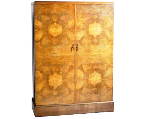 A 1930's Art Deco gentleman's compactum wardrobe of walnut construction having twin full length doors with shaped brass handl