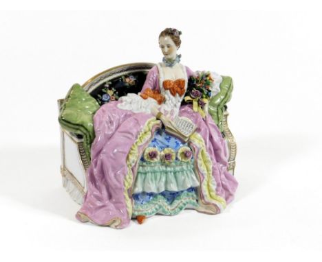 Y.E. MUELLER. A German late 19th century porcelain figure by Y.E. Mueller & Co., lady reading on a sofa. Max. width 20cm.  Pl