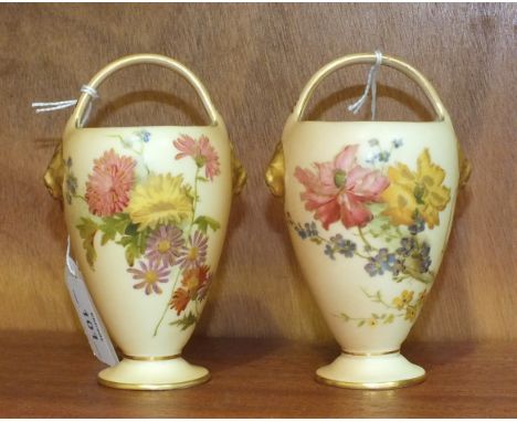 Two Royal Worcester posy baskets with painted floral decoration and gilt lion masks, on blush ground, 13cm high, with printed