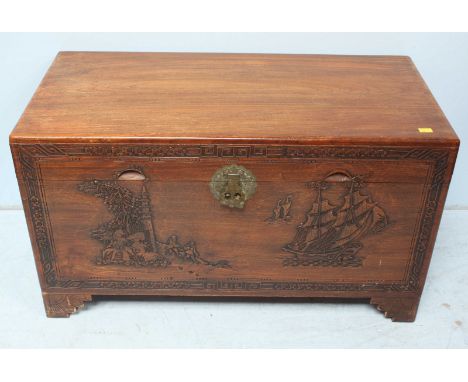 A 20th Century camphor wood trunk, the front decorated with a junk and figures standing by a pagoda. 104cm wide.