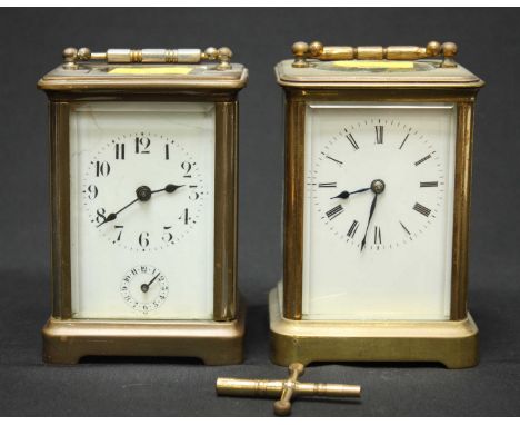 Two brass carriage clocks with white enamel dials.