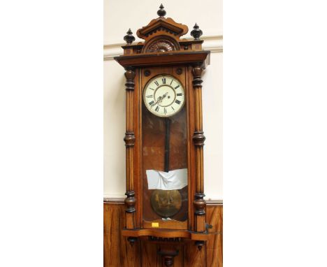 A walnut cased Vienna wall clock, 8-day movement striking a gong, enamel dial with Roman numerals, the case with baroque pedi