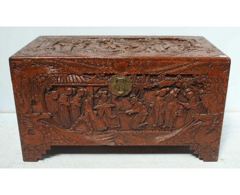 A large Chinese carved camphor wood trunk, carved allover with figures and landscapes, 98 cm wide.